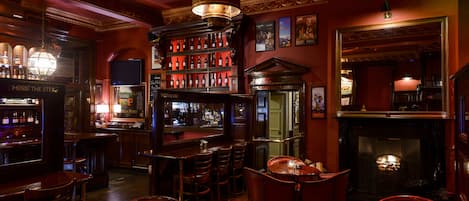 Zona de bar con muebles de madera, una alacena para vinos y una chimenea.