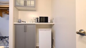 A compact kitchen with a microwave, coffee maker, and a white refrigerator. - Maple Leaf Motel (Goderich)