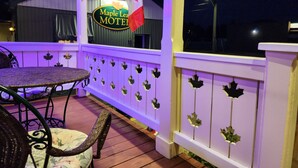 A porch with a maple leaf flag, a sign for Maple Leaf Motel, and a table with chairs.