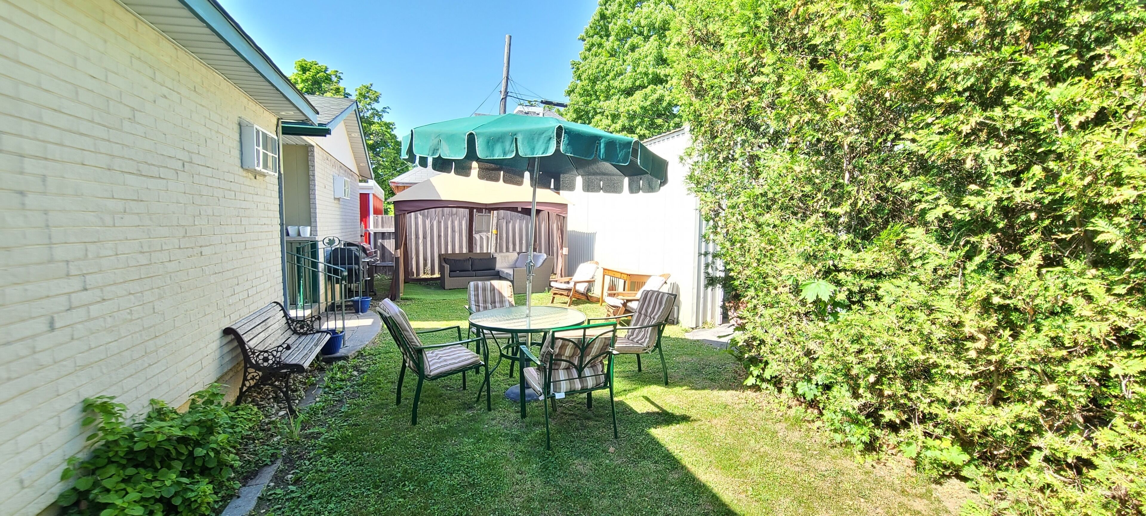 Un jardin avec un espace patio, un barbecue et un coin salon abrité.