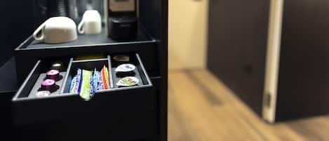 A coffee machine with a coffee pot, two cups, and a selection of coffee pods.