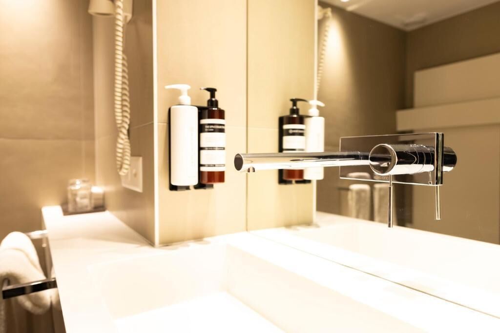 Un baño moderno con un perchero para toallas, un dispensador de papel higiénico y dos botellas de jabón líquido.