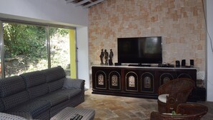 A living room with a sofa, a television, and a wicker chair. - Banana Leaf Eco Hostel (Rio de Janeiro)