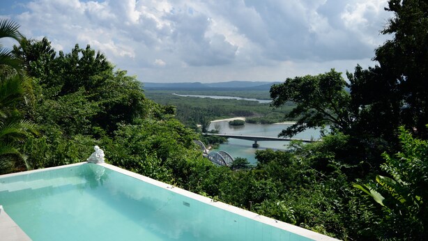 A swimming pool with a view of a river and bridge in the background. - Banana Leaf Eco Hostel (Rio de Janeiro)