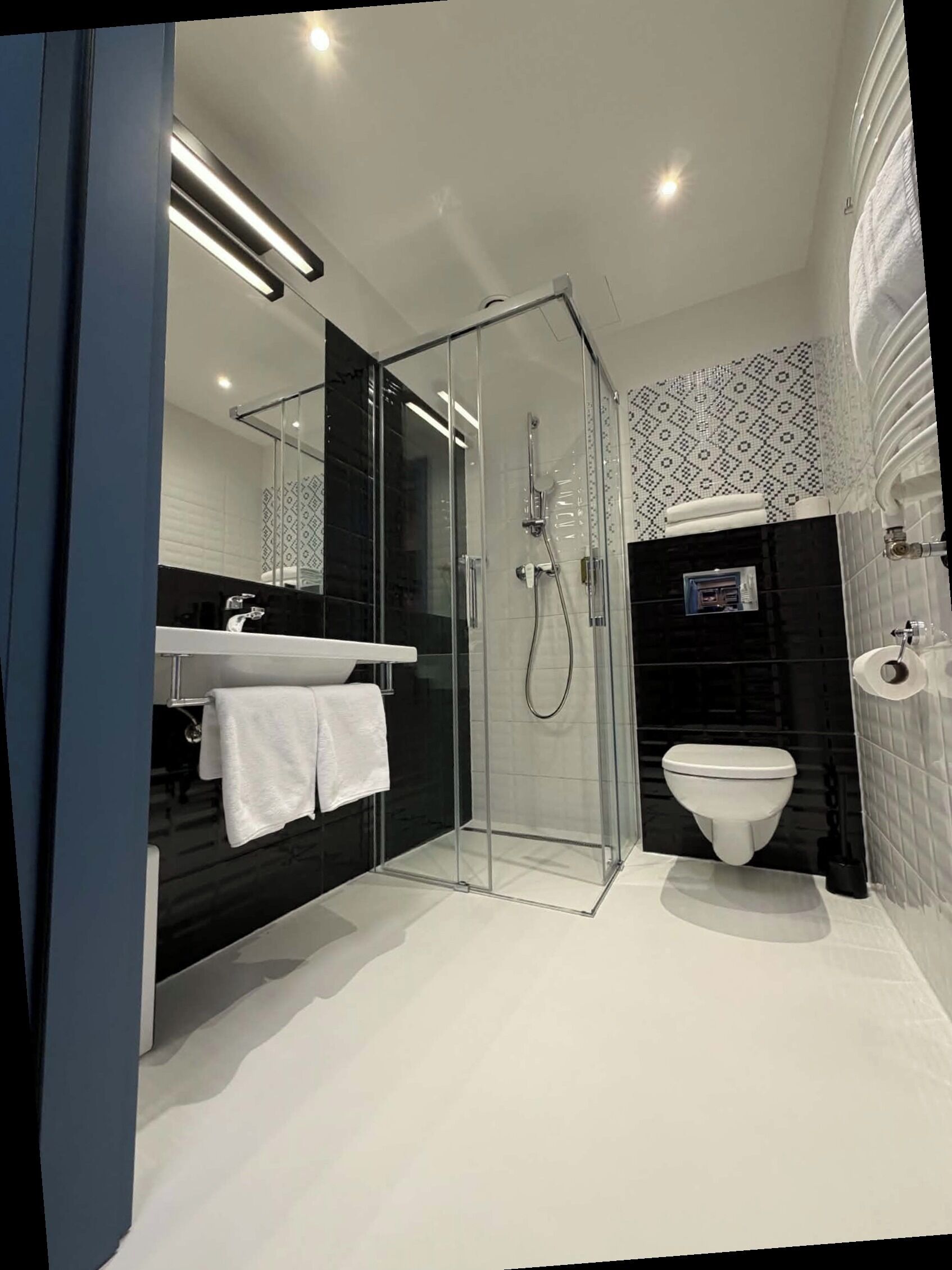 Une salle de bain moderne avec une douche à parois de verre, des toilettes blanches et un lavabo noir avec une serviette.