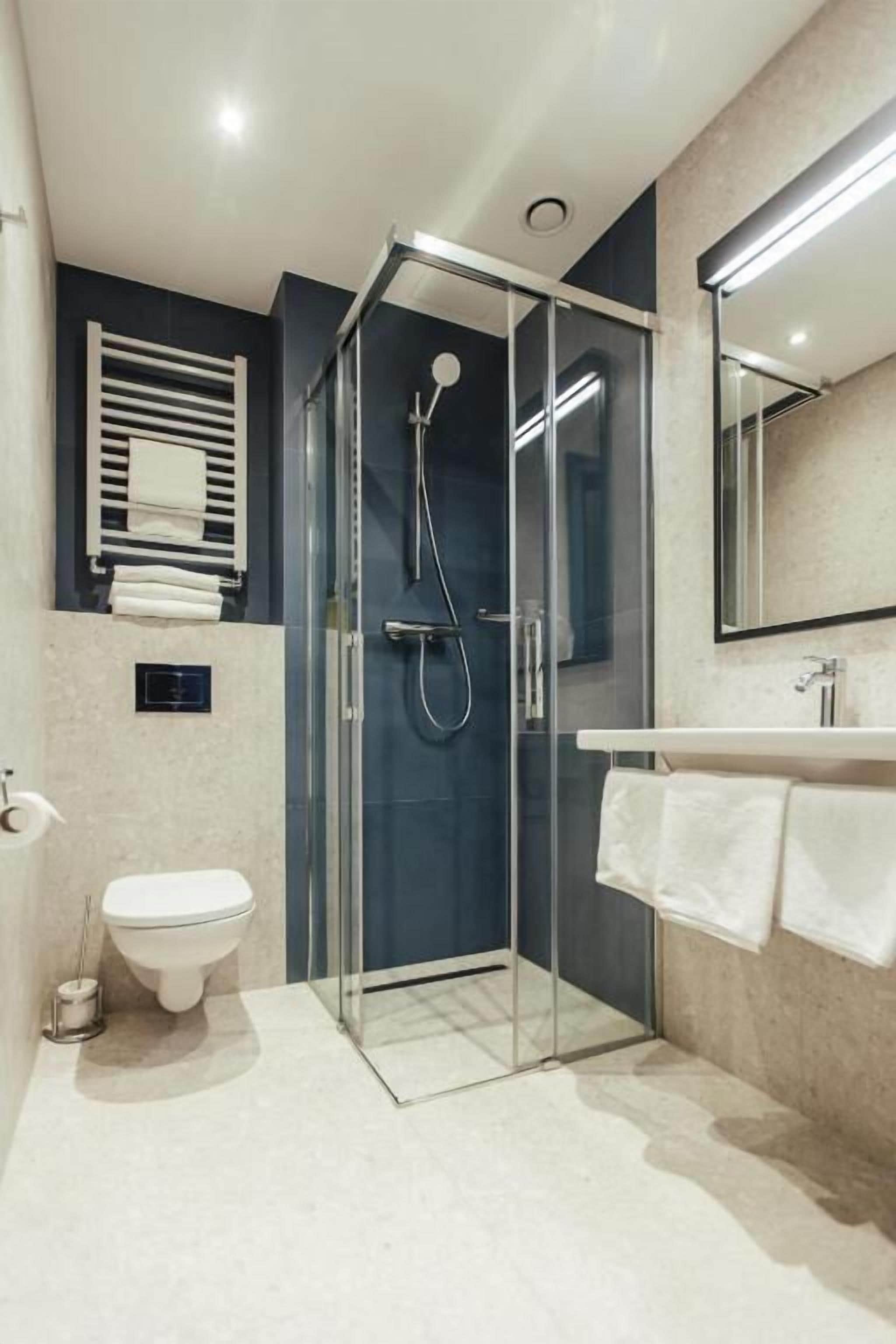 Une salle de bain moderne avec une douche à parois de verre, des toilettes et un lavabo équipé d’un porte-serviettes.