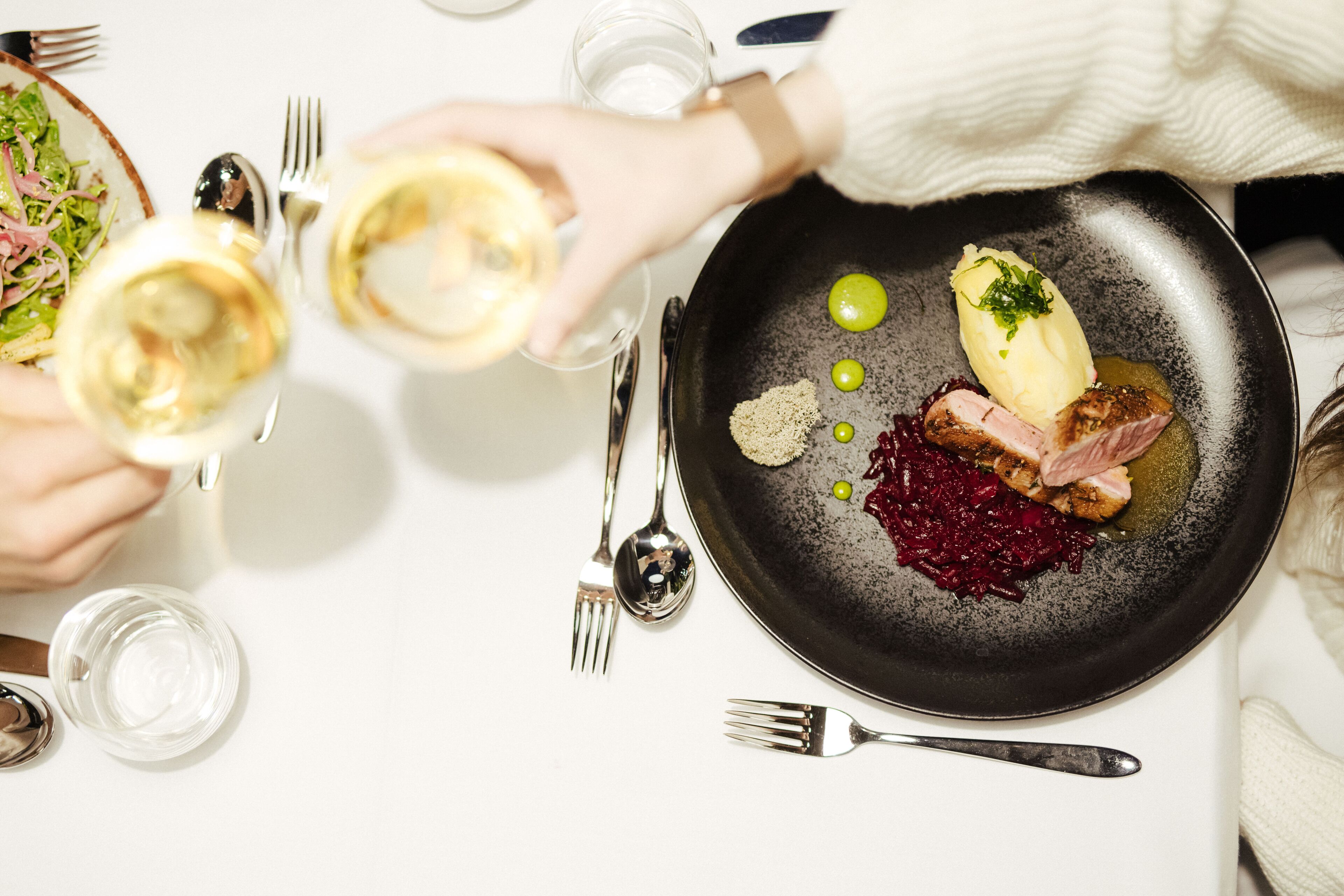 A dining table with a black plate containing food, a fork, and a spoon.