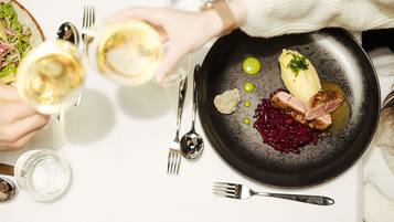 A dining table with a black plate containing food, a fork, and a spoon.