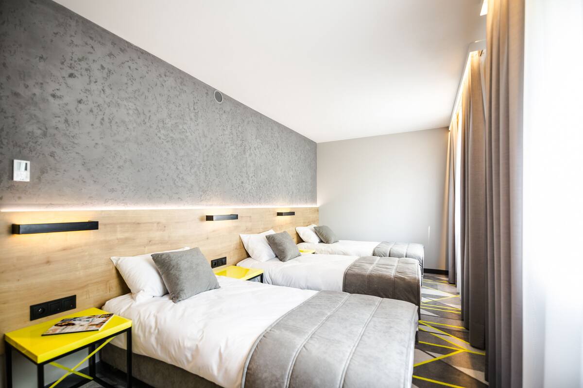 A hotel room with two beds, a wooden headboard, a yellow side table, and a modern design.