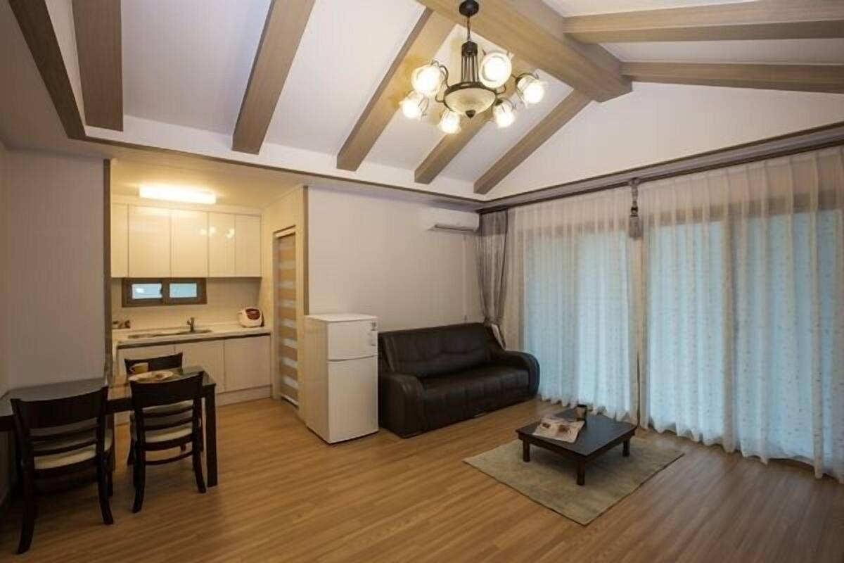 Een compact woongedeelte met een kitchenette, een eethoek, een bank en een salontafel.
