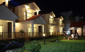 A multi-story hotel with illuminated balconies and a well-lit outdoor seating area. - Soranghozen Pension (Seogwipo)