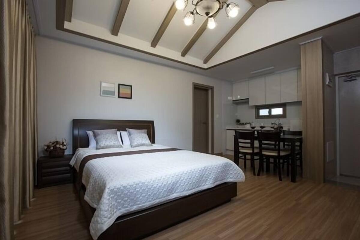 Een slaapkamer met een groot bed, een bureau en een kitchenette.