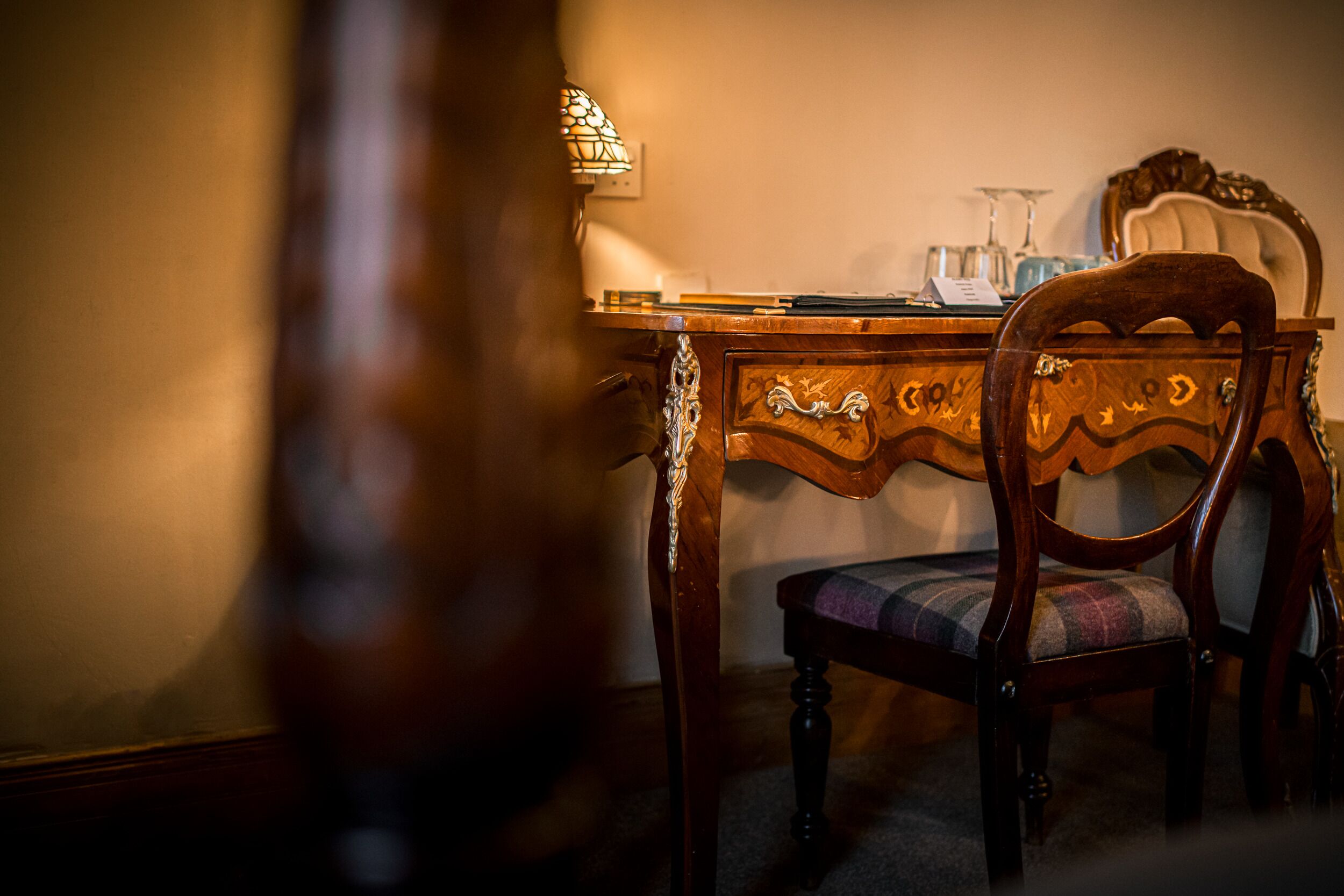 Une table à manger avec une chaise, une lampe et un ensemble de verres posés sur la table.