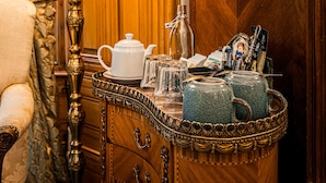 Een houten dressoir met een lamp, theepot en glazen.