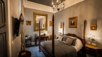 Un dormitorio con cama con dosel, candelabro, espejos ornamentados y cuadros en las paredes.