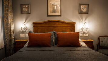 A neatly made bed with a wooden headboard, two wall-mounted lamps, and three framed pictures on the wall.