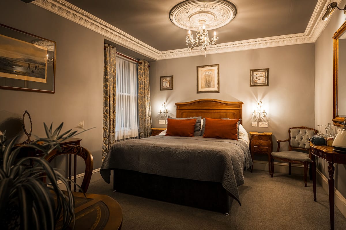 Une chambre bien aménagée, dotée d’un grand lit, de deux tables de chevet, d’une chaise et d’un bureau.