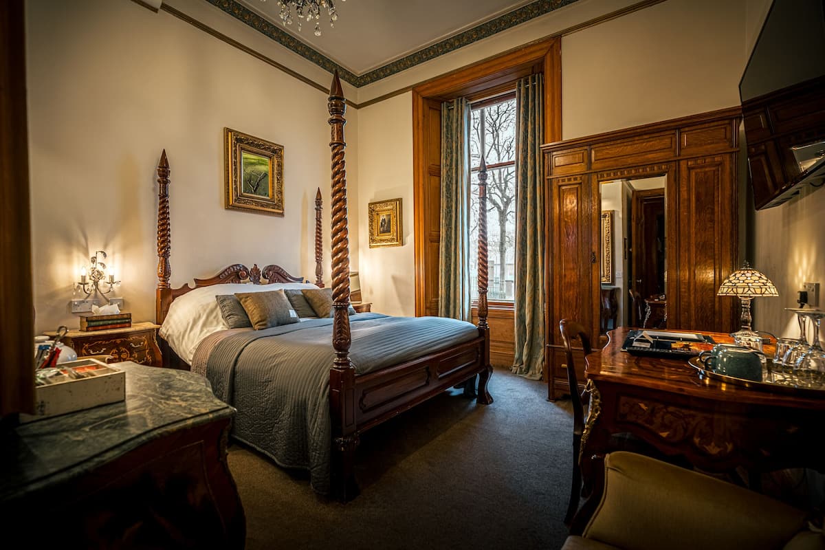 Une chambre à coucher de style traditionnel, avec un lit à baldaquin, une commode en bois et un grand miroir.