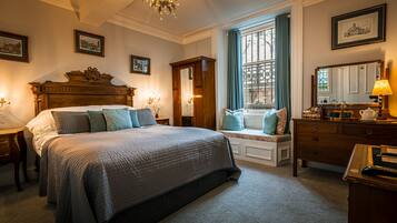 A bedroom with a large bed, a dresser, a vanity with a mirror, and a window with curtains.