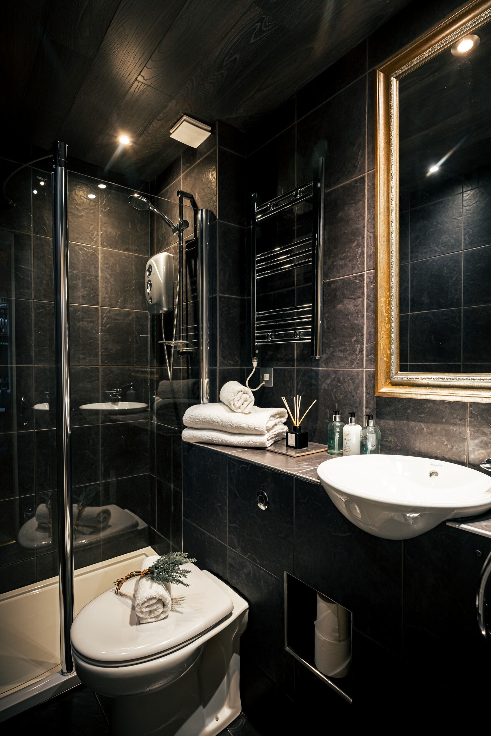 A modern bathroom with a glass-enclosed shower, a white sink, and a toilet.