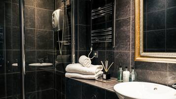 A modern bathroom with a glass-enclosed shower, a white sink, and a toilet.