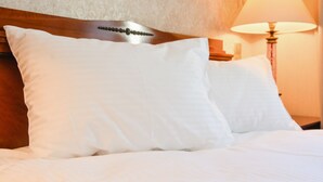 A neatly made bed with white linens and a wooden headboard. - Komoda Club Residence (Kalisz)