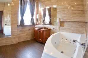 A modern bathroom with a large bathtub, a vanity with a sink, and a mirror above the vanity. - Komoda Club Residence (Kalisz)