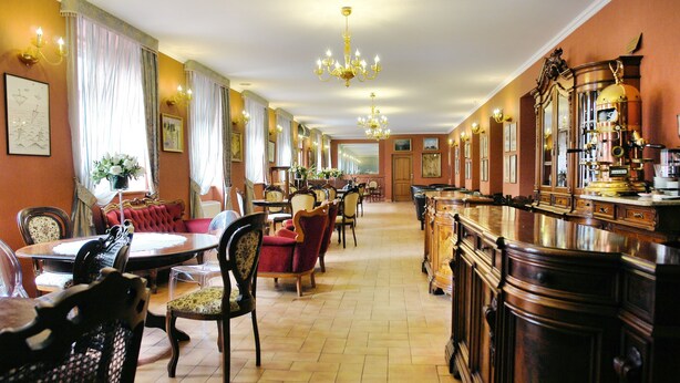 A hotel lobby with a long bar, multiple seating areas, and a chandelier. - Komoda Club Residence (Kalisz)