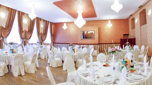 A banquet hall with round tables set for dining, white chairs, and chandeliers. - Komoda Club Residence (Kalisz)