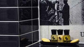 Un baño con azulejos negros, un lavabo y tres botellas de jabón artesanal Duck Island.