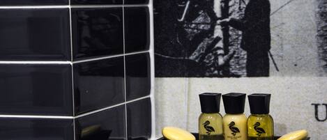 A bathroom with black tiles, a sink, and three bottles of Duck Island hand soap.