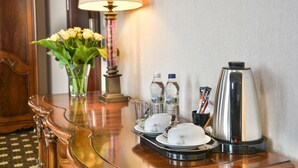 A hotel room with a wooden sideboard, a vase of flowers, a lamp, a tray with cups and a coffee maker. - Komoda Club Residence (Kalisz)