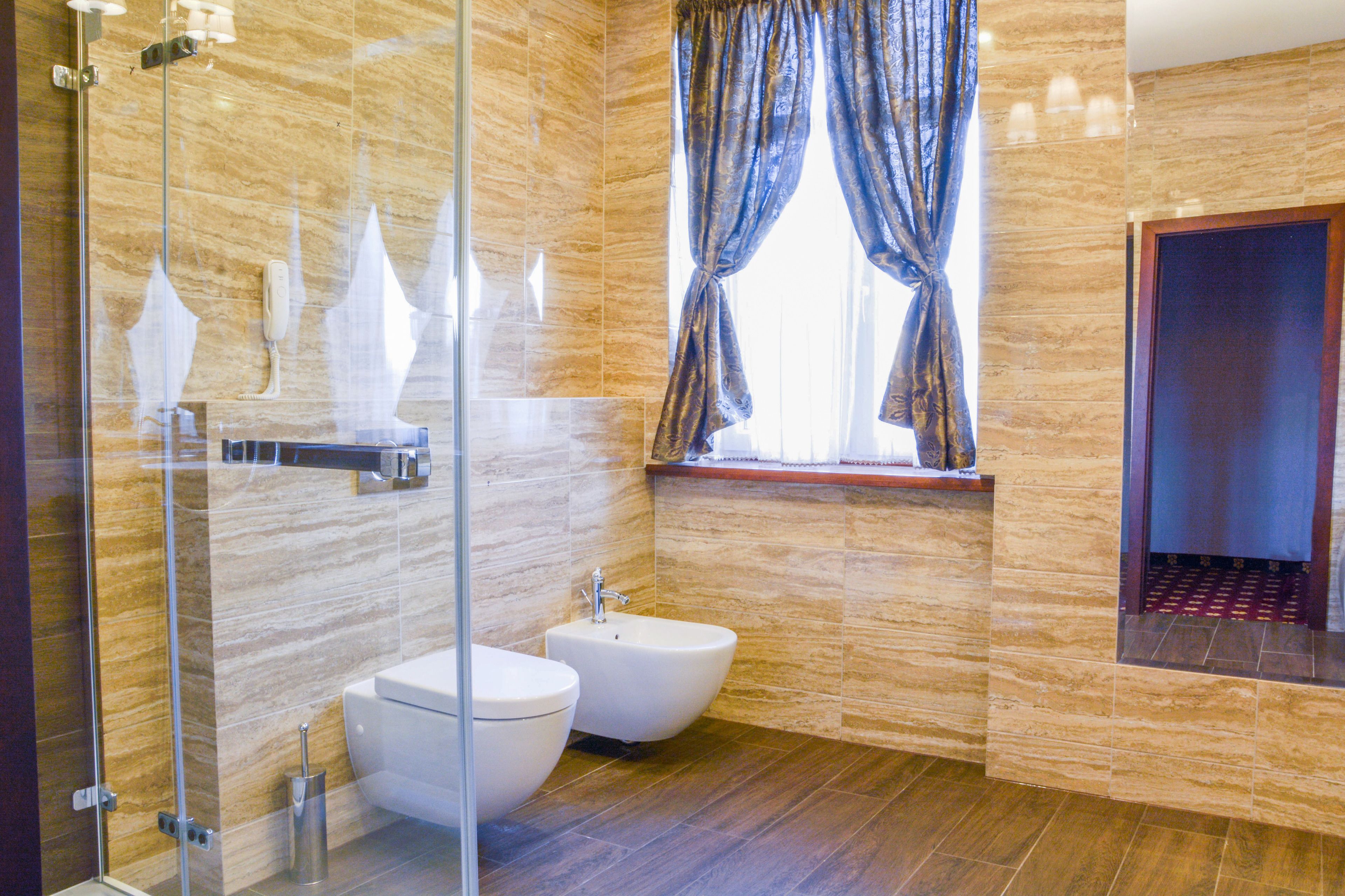 A modern bathroom with a glass shower enclosure, a bidet, a toilet, and a vanity with a mirror.