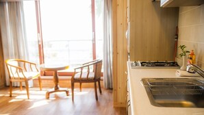 A modern kitchen with a stainless steel sink, wooden cabinets, and a dining area with a table and chairs. - Living Stone Pension (Seogwipo)