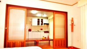 A hotel room with a sliding door leading to a kitchen area. - Living Stone Pension (Seogwipo)