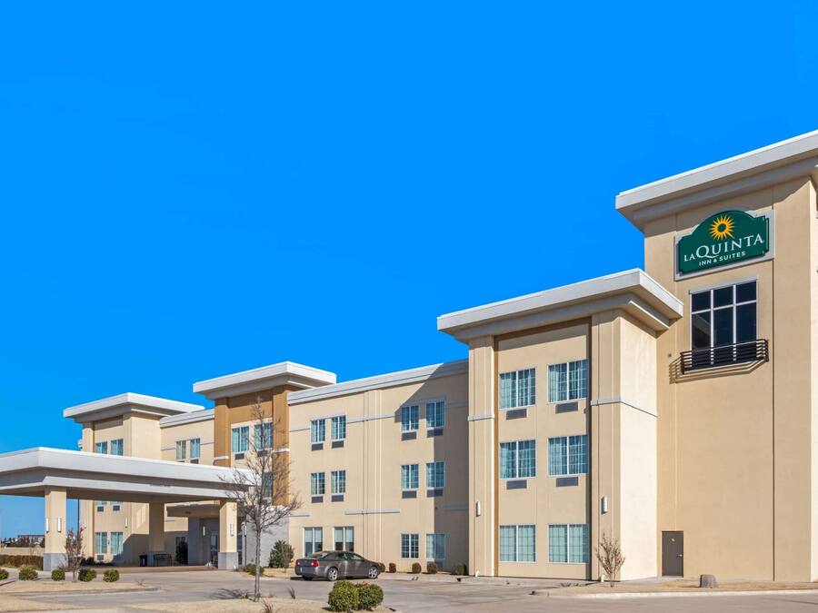 Edifício La Quinta Inn & Suites com design moderno, múltiplos acessos e céu azul límpido.