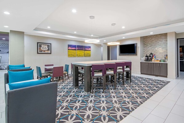 A modern hotel room with a dining area, a kitchen, and a TV.