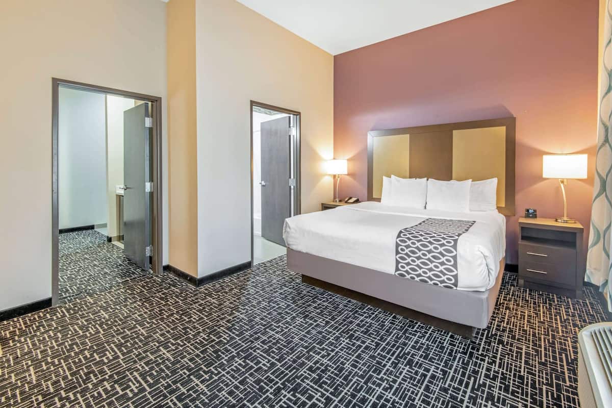 Una habitación de hotel con una cama grande, mesitas de noche, un espejo y una alfombra estampada.