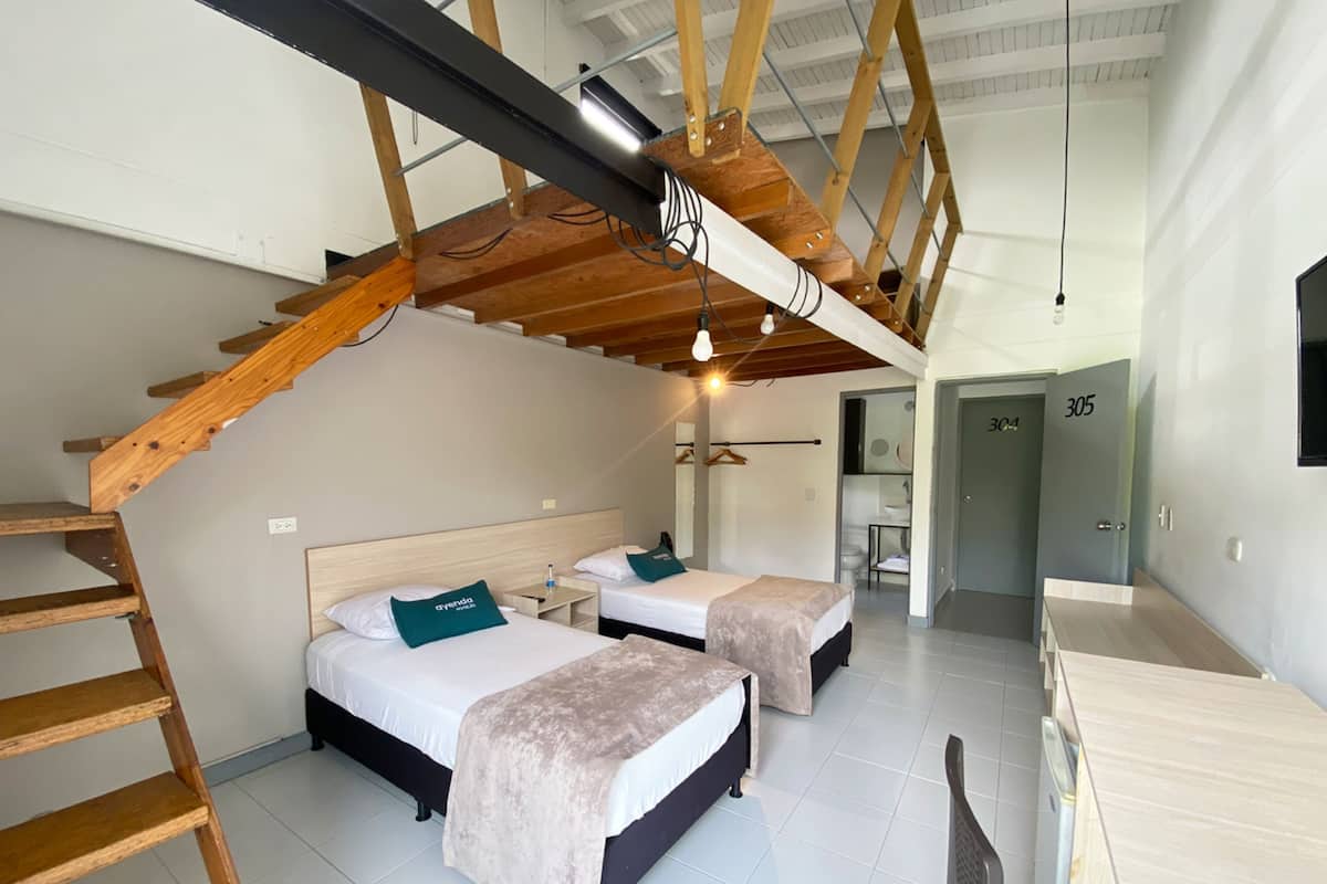 Ein modernes Hotelzimmer mit zwei Betten, einer Holztreppe und einem Schreibtisch.