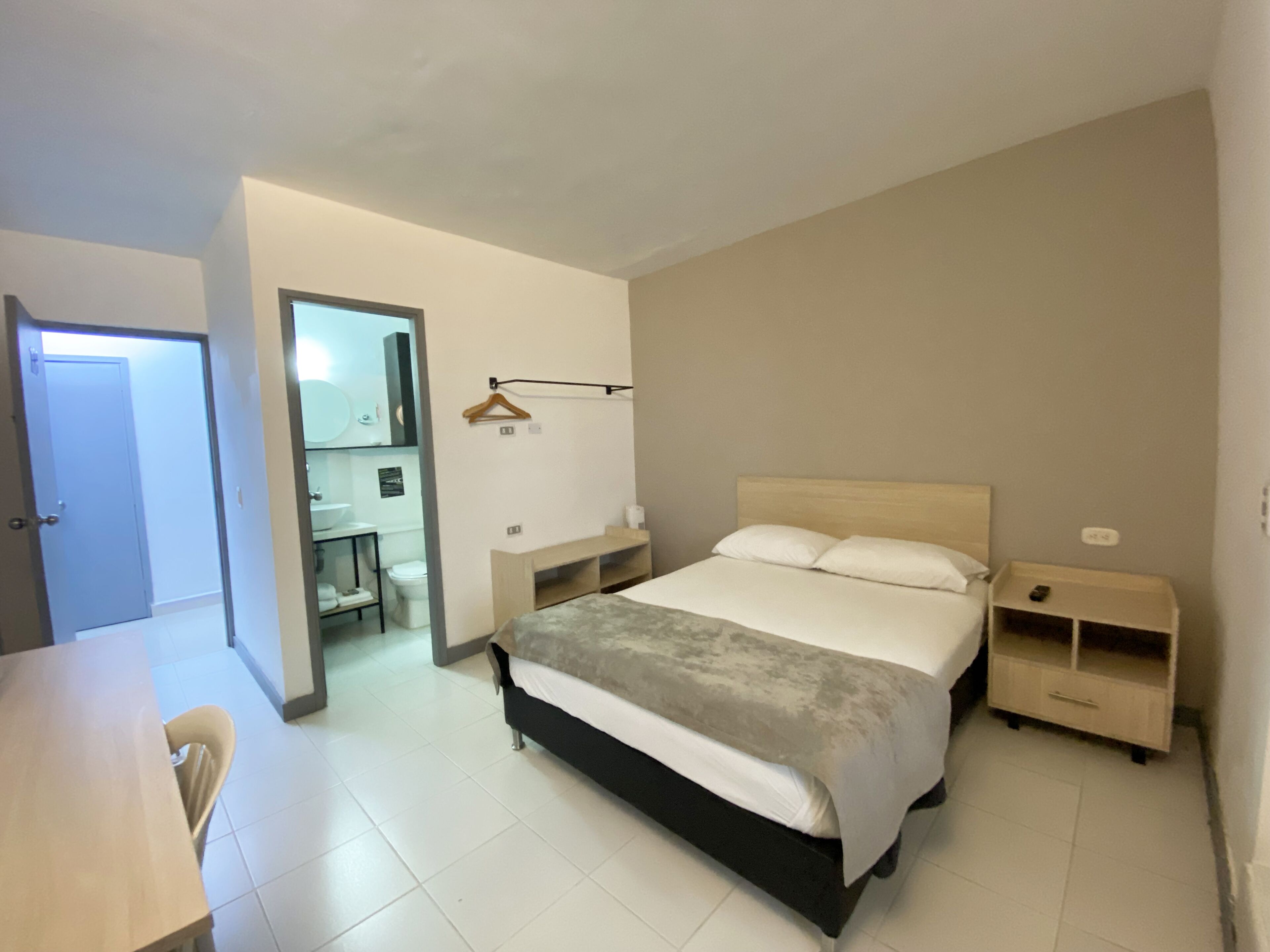 A bedroom with a bed, bedside tables, a desk, and a chair.