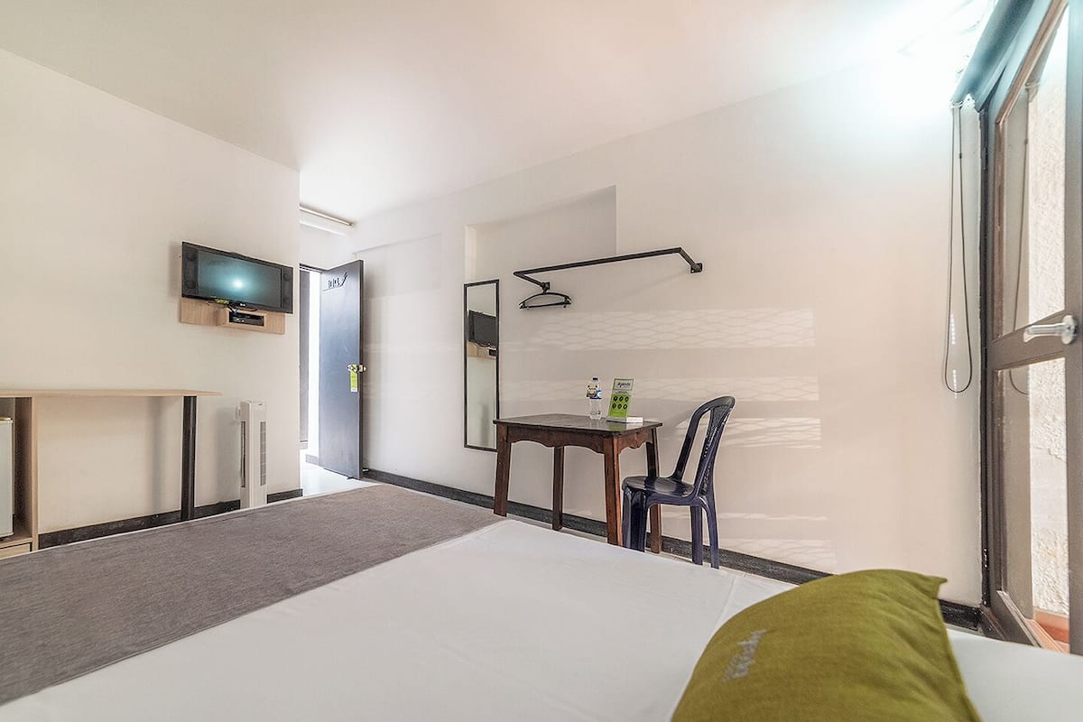 Ein Hotelzimmer mit Bett, Schreibtisch, Stuhl, Fernseher und Fenster.