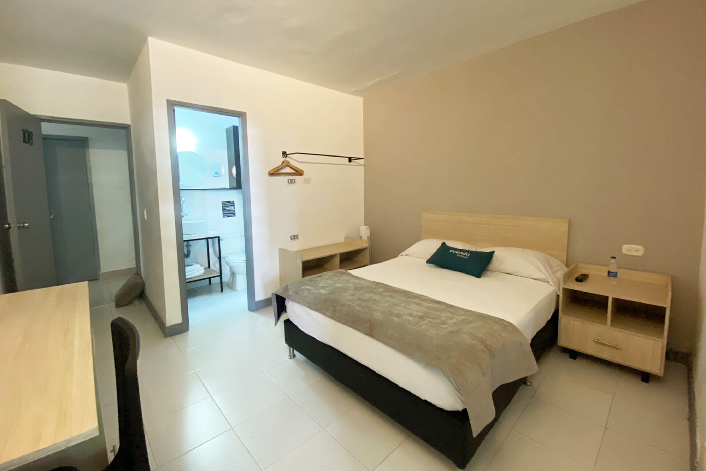 A bedroom with a bed, bedside table, and a small desk with a chair.