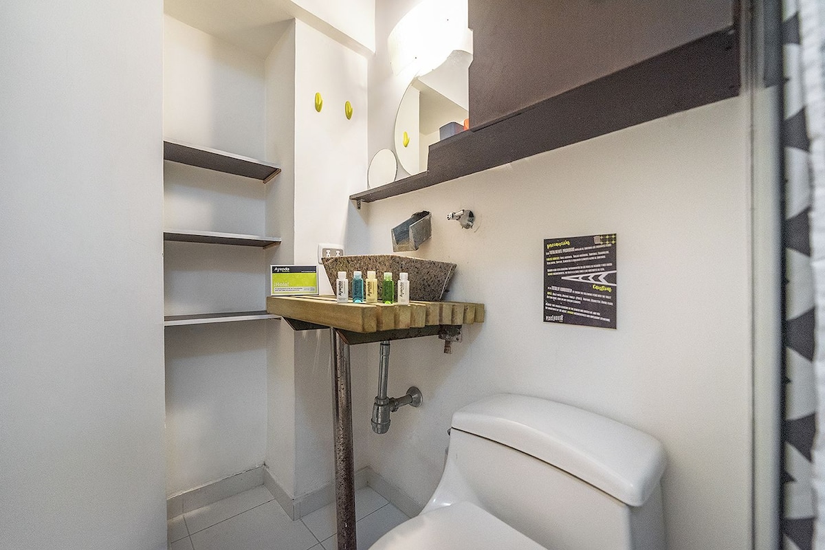 Ein kleines Badezimmer mit Toilette, Waschbecken, Pflegeutensilien und einem Spiegel.