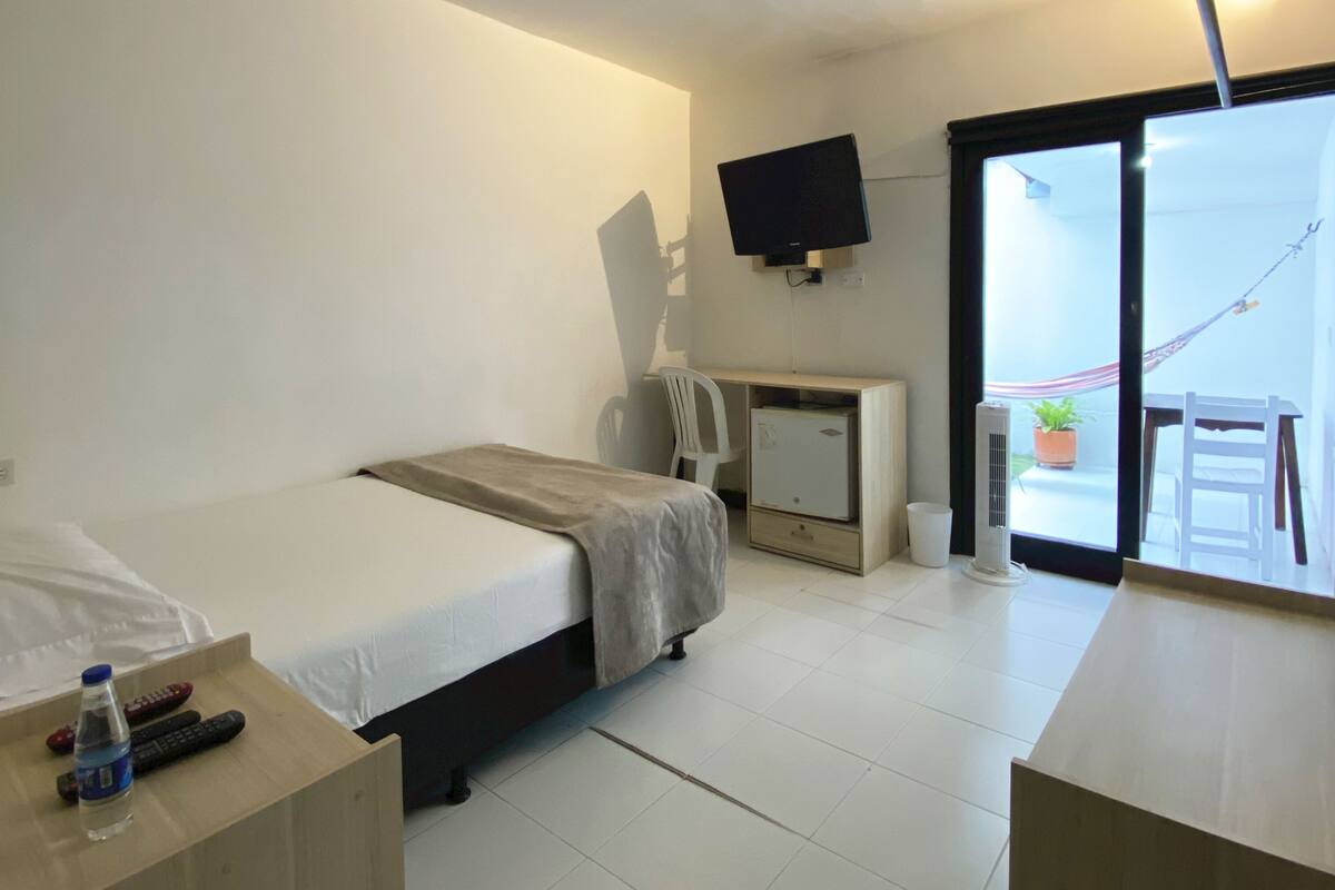 Ein Hotelzimmer mit Bett, Schreibtisch, Stuhl, Fernseher und einem Balkon mit Hängematte.