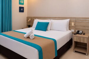 Habitación de hotel con cama, mesita de noche, teléfono y decoración de estrella y arrecife de coral en la pared.