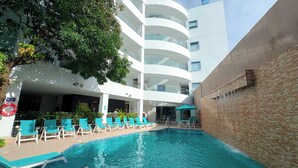 A pool area with lounge chairs and a building with multiple balconies. - Hotel Portobelo Plaza las Ámericas (San Andrés)