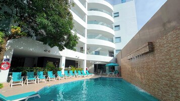 Una piscina al aire libre, sombrillas, sillones reclinables de piscina