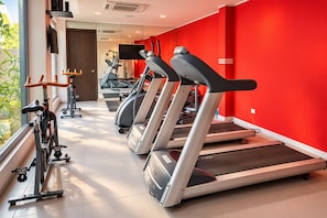 Un gimnasio con cintas de correr, bicicletas estáticas y equipo de ejercicio.
