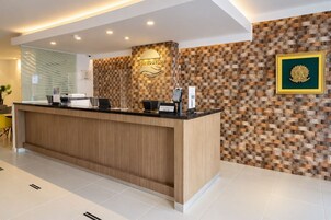 A hotel reception desk with a wooden counter, a reception area, and a wall with a patterned design.