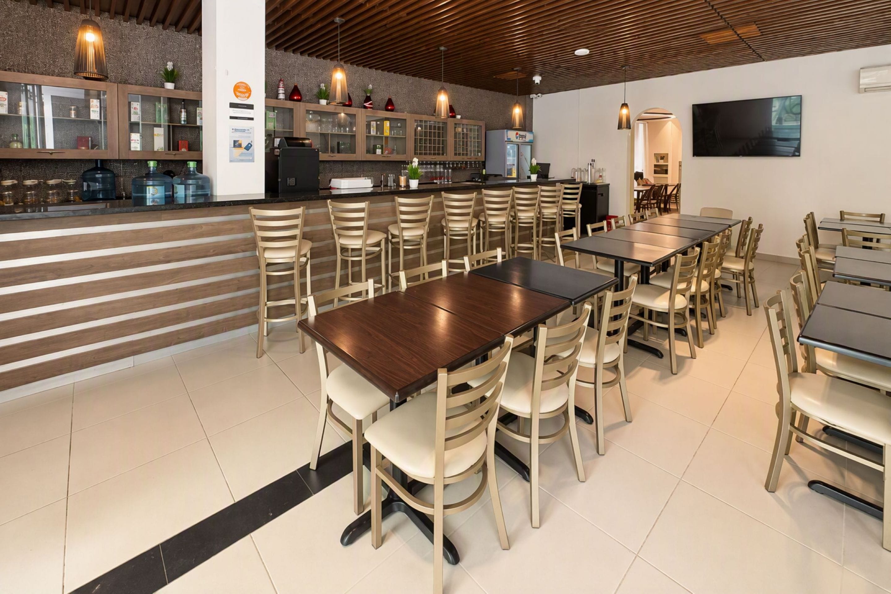 Un restaurante con barra, varias mesas y sillas.
